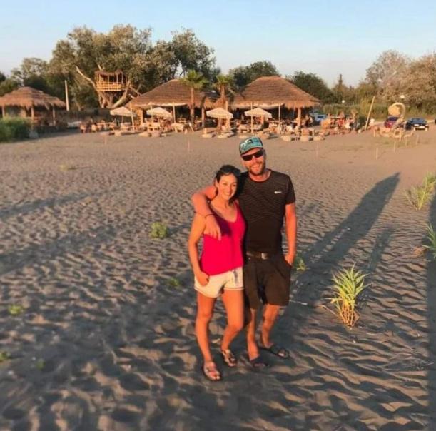 Daria und Toni, Gastgeber von Solanas View, am Strand mit Resort im Hintergrund – Über uns Montenegro